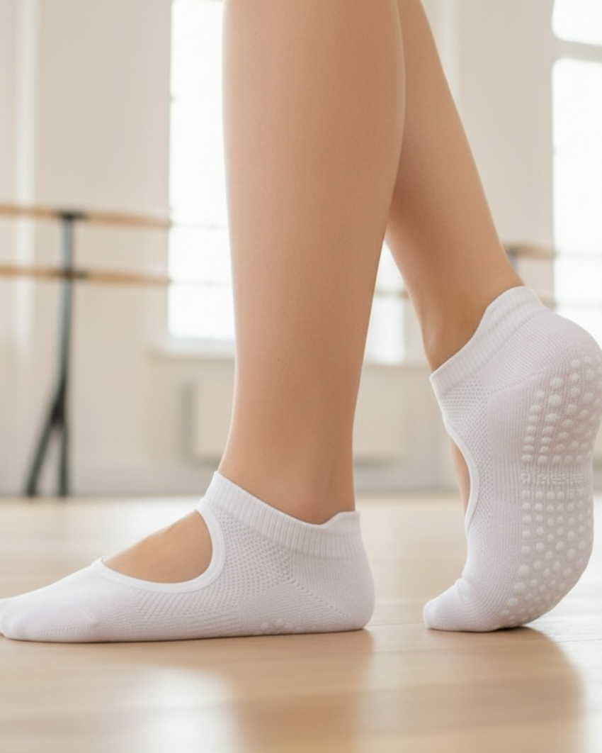 White socks with non-slip sole worn by a person on a light wooden floor.